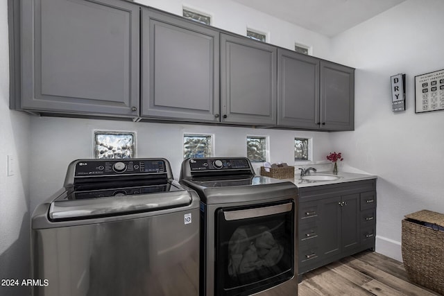 clothes washing area with cabinets, hardwood / wood-style flooring, separate washer and dryer, and sink