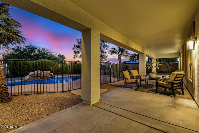 patio terrace at dusk with an outdoor hangout area and a fenced in pool