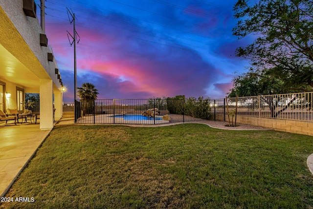 yard at dusk featuring a fenced in pool and a patio