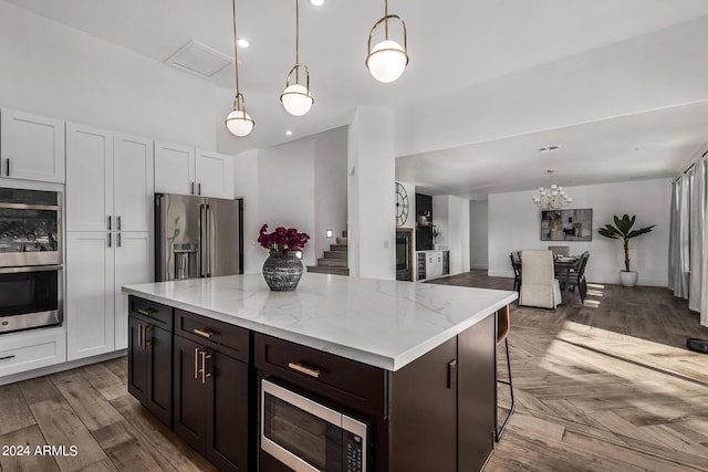 kitchen with a center island, dark brown cabinets, hanging light fixtures, stainless steel appliances, and white cabinets