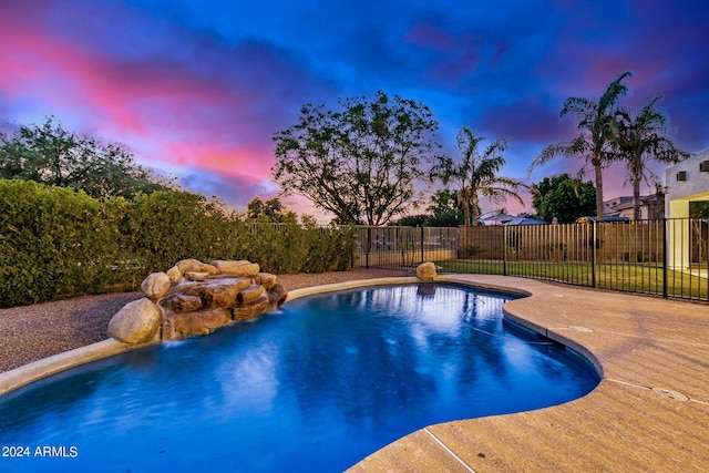 pool at dusk featuring a patio and pool water feature