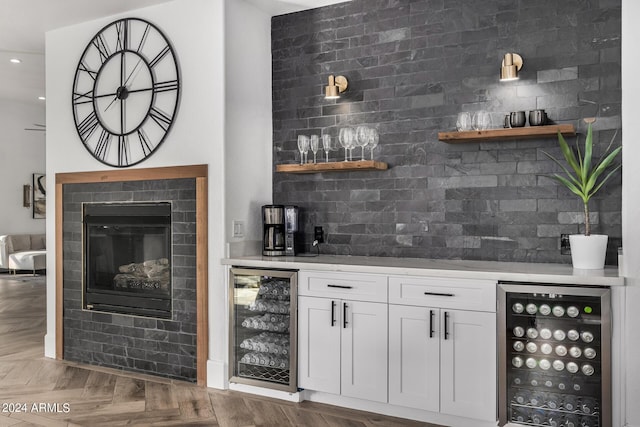 bar with tasteful backsplash, parquet flooring, beverage cooler, and white cabinets