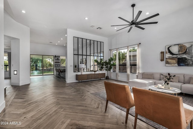 living room featuring ceiling fan, parquet flooring, a high ceiling, and a wealth of natural light