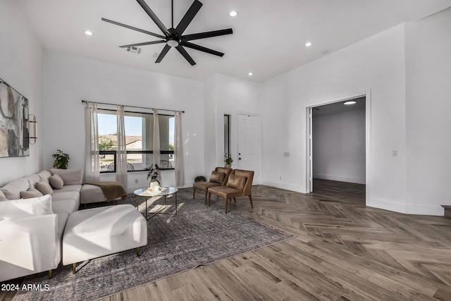 living room featuring parquet flooring, a towering ceiling, and ceiling fan