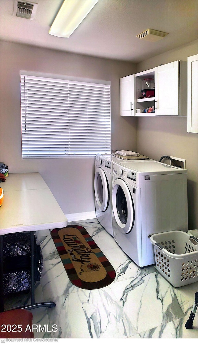 washroom featuring cabinets and washer and clothes dryer