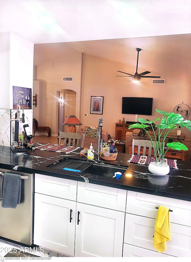 kitchen with sink, ceiling fan, dishwasher, white cabinets, and vaulted ceiling