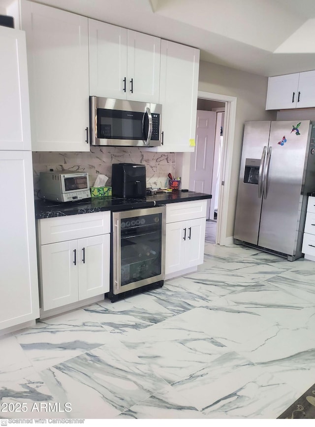 kitchen featuring stainless steel appliances, white cabinets, wine cooler, and backsplash