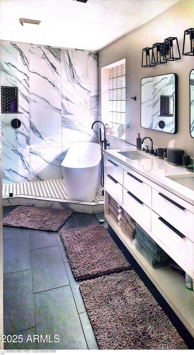 bathroom with tile patterned floors, vanity, a bathtub, and a textured ceiling