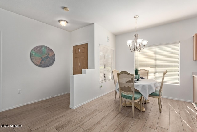 dining area with baseboards, a chandelier, and light wood-style floors