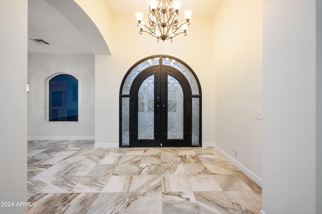 entryway featuring a towering ceiling, french doors, and an inviting chandelier