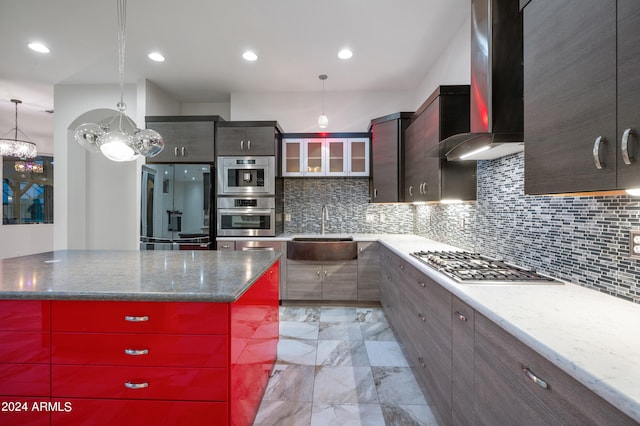 kitchen featuring sink, decorative light fixtures, wall chimney range hood, stainless steel appliances, and a center island