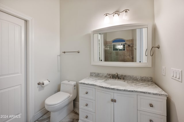 bathroom featuring toilet, tiled shower, and vanity