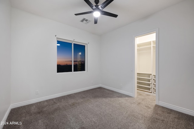 unfurnished bedroom featuring carpet floors, a spacious closet, a closet, and ceiling fan