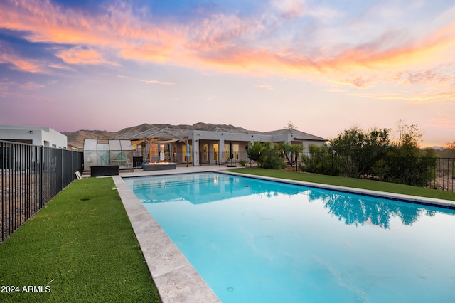 pool at dusk with a lawn and a patio area