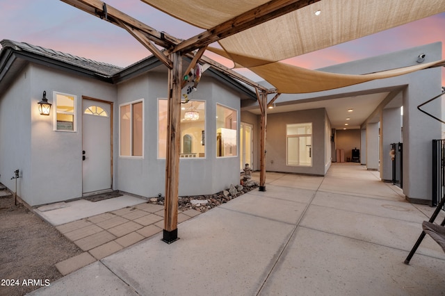 exterior entry at dusk featuring a patio