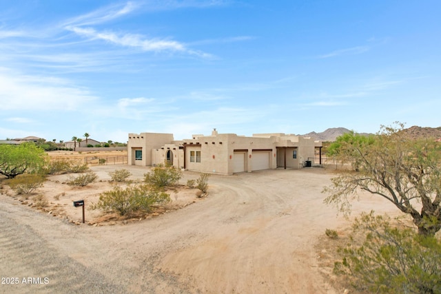 11266 W Calle Con Queso, Casa Grande, AZ 85194 - pueblo-style house with stucco siding, a garage, dirt driveway, and a mountain view