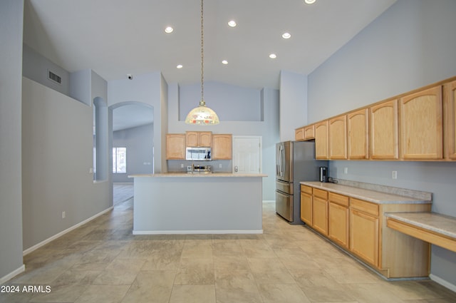 kitchen featuring appliances with stainless steel finishes, light brown cabinetry, a kitchen island with sink, decorative light fixtures, and high vaulted ceiling