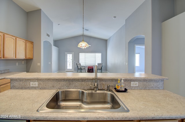 kitchen featuring light brown cabinets, sink, hanging light fixtures, and vaulted ceiling