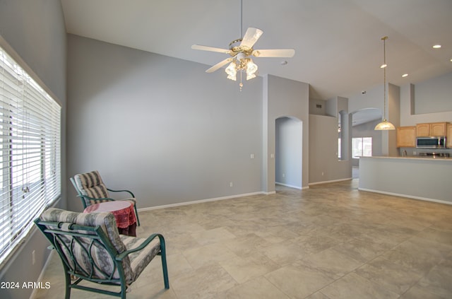 living area with high vaulted ceiling, ceiling fan, and a wealth of natural light