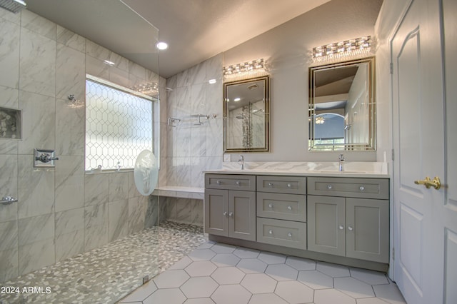 bathroom with tile patterned floors, vanity, a tile shower, and lofted ceiling