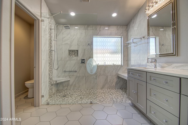 bathroom with a tile shower, tile patterned floors, vanity, and toilet