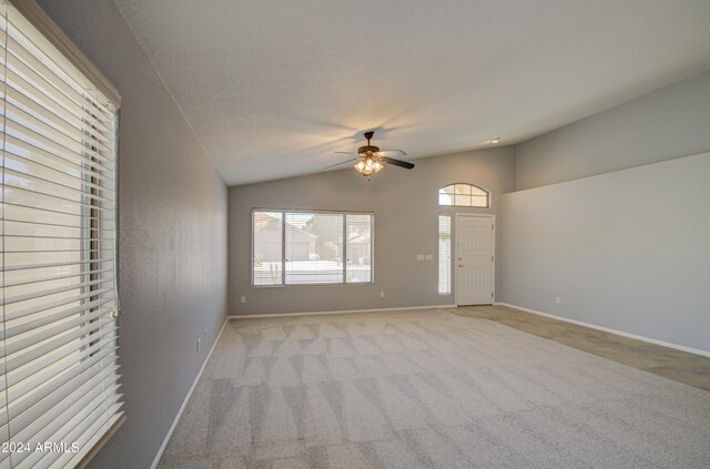 unfurnished living room featuring a textured ceiling, light colored carpet, ceiling fan, and lofted ceiling