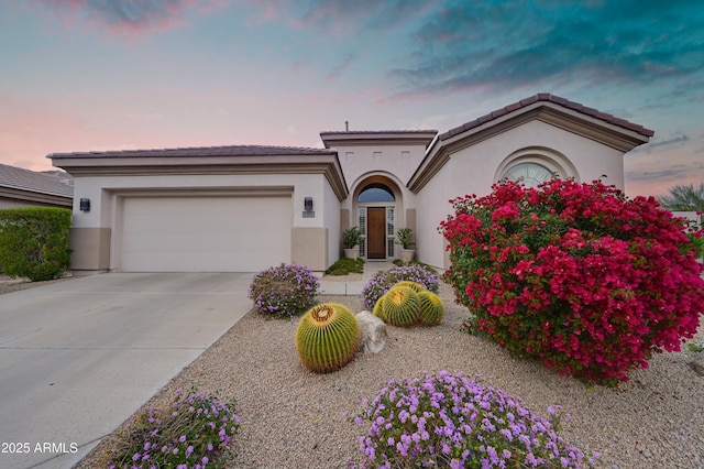 mediterranean / spanish-style house featuring stucco siding, an attached garage, and driveway