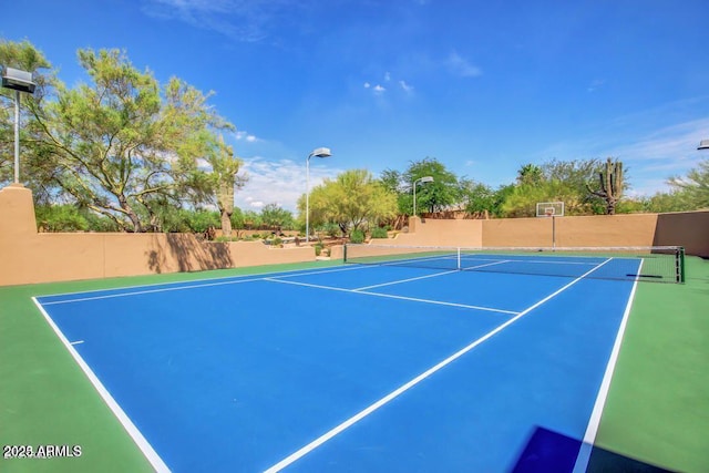 view of tennis court with community basketball court and fence