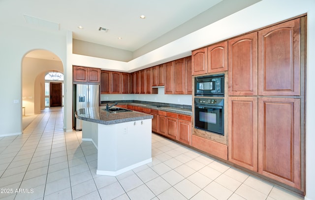 kitchen featuring light tile patterned floors, visible vents, a sink, black appliances, and dark countertops