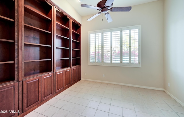 empty room featuring light tile patterned floors, ceiling fan, and baseboards