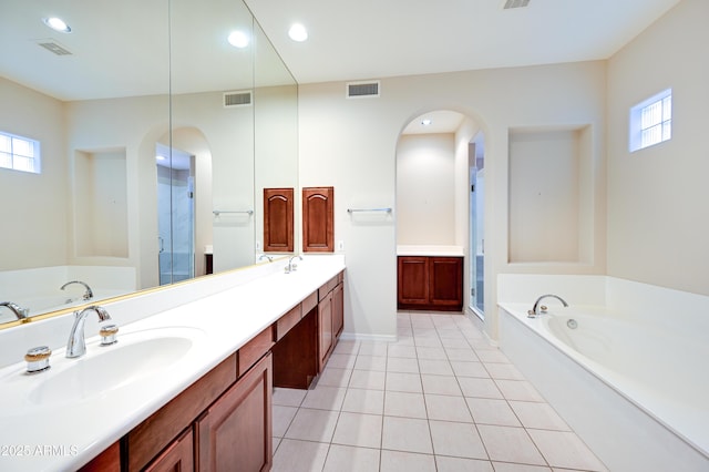 bathroom with a garden tub, visible vents, and a sink