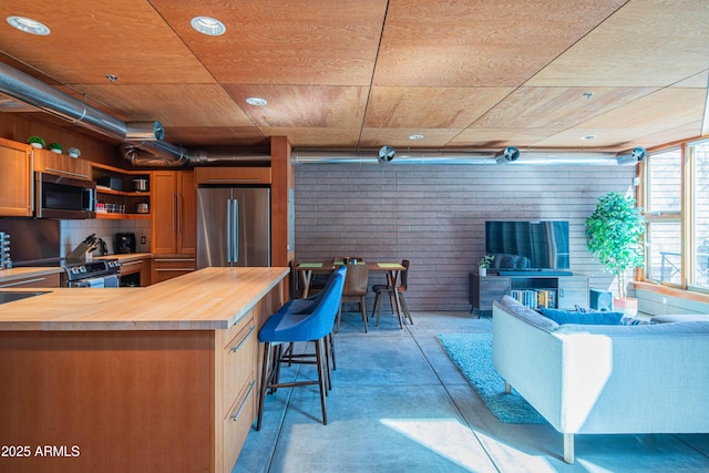 kitchen with a kitchen bar, butcher block counters, open floor plan, and stainless steel appliances