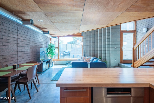 interior space featuring butcher block counters, brick wall, and concrete floors