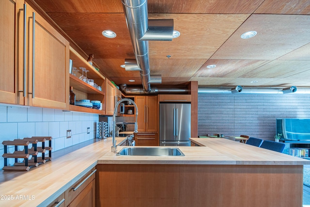 kitchen with backsplash, wooden ceiling, a peninsula, freestanding refrigerator, and wood counters