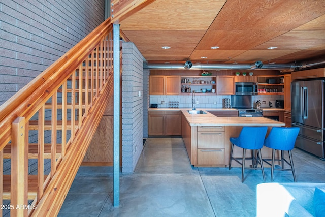 kitchen with tasteful backsplash, finished concrete flooring, light countertops, appliances with stainless steel finishes, and open shelves