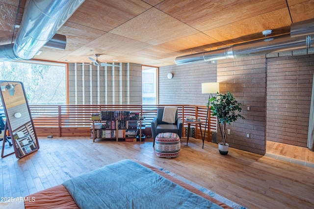 sitting room with wooden ceiling, plenty of natural light, wood finished floors, and brick wall