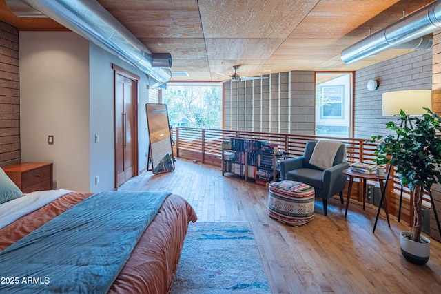 bedroom featuring expansive windows, brick wall, and hardwood / wood-style flooring