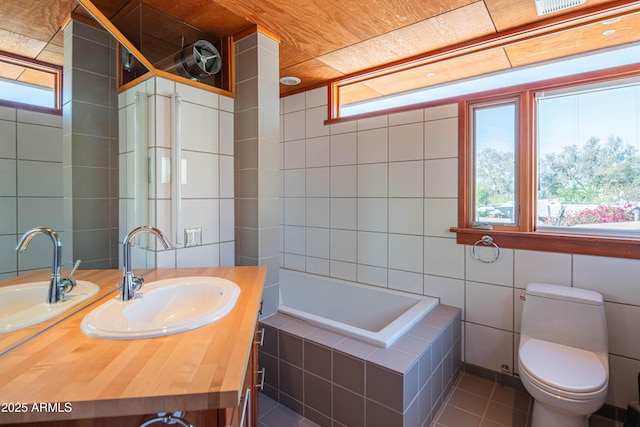 bathroom featuring vanity, tile walls, tile patterned flooring, and tiled bath