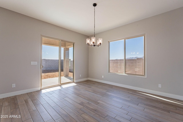 unfurnished room with a chandelier and wood-type flooring