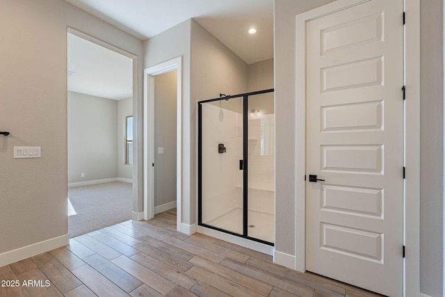 bathroom with hardwood / wood-style flooring and an enclosed shower