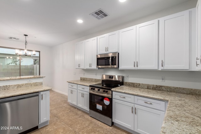 kitchen with stainless steel appliances, light tile patterned floors, an inviting chandelier, white cabinets, and hanging light fixtures