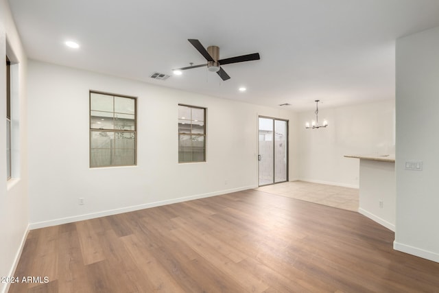 empty room featuring light hardwood / wood-style floors and ceiling fan with notable chandelier