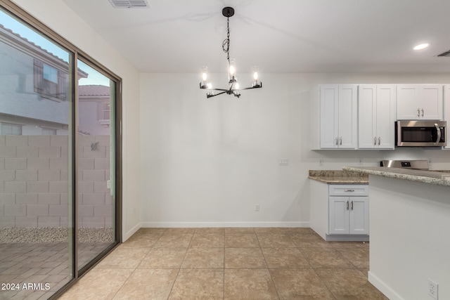 kitchen with white cabinets, light stone countertops, light tile patterned floors, decorative light fixtures, and a chandelier