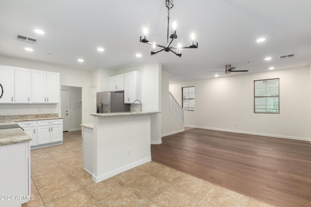 kitchen featuring white cabinetry, stainless steel fridge with ice dispenser, light hardwood / wood-style floors, decorative light fixtures, and ceiling fan with notable chandelier