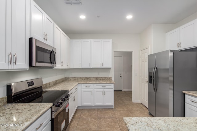 kitchen featuring white cabinets, light tile patterned floors, stainless steel appliances, and light stone counters