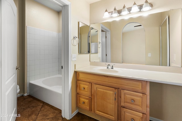 full bathroom with tile patterned floors, tiled shower / bath, vanity, and toilet