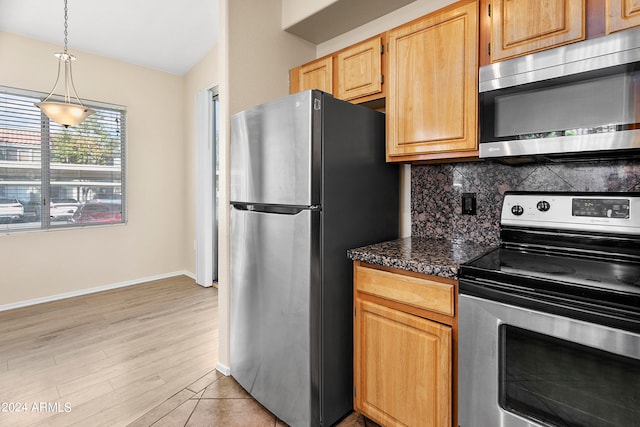 kitchen featuring pendant lighting, light wood-type flooring, tasteful backsplash, appliances with stainless steel finishes, and dark stone counters