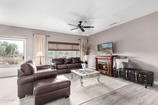 living room featuring a wealth of natural light, light hardwood / wood-style flooring, and ceiling fan