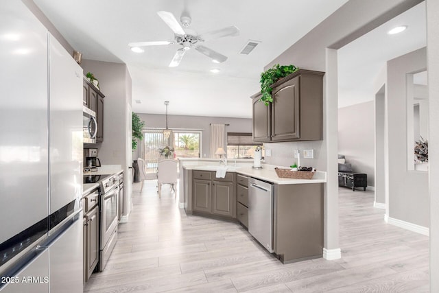 kitchen with stainless steel appliances, ceiling fan, light hardwood / wood-style floors, and decorative light fixtures