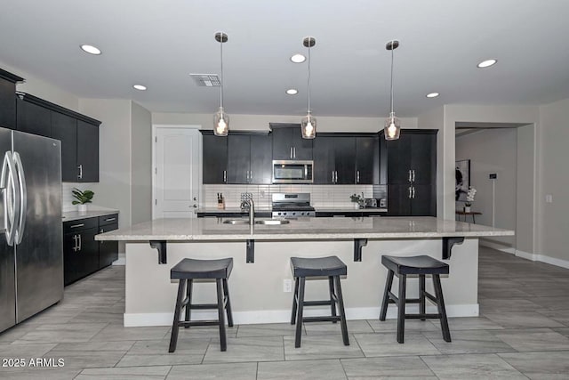 kitchen with a kitchen breakfast bar, hanging light fixtures, sink, a center island with sink, and stainless steel appliances